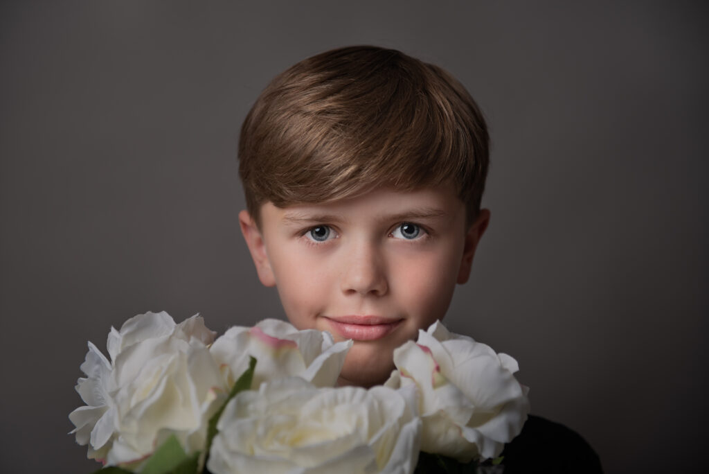 a headshot of a boy holding a bunch pf flowers which highlights the kindness in his eyes.