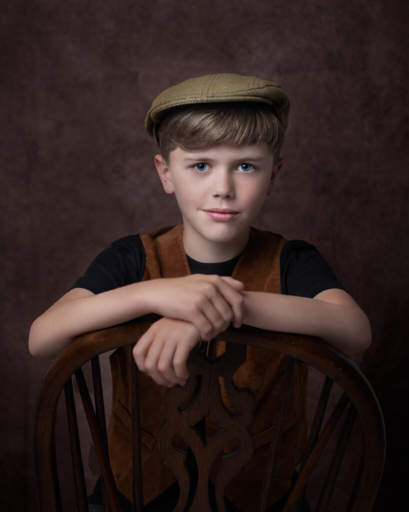 A vintage styled fine art portrait of a boy wearing a waistcoat and a flat cap.